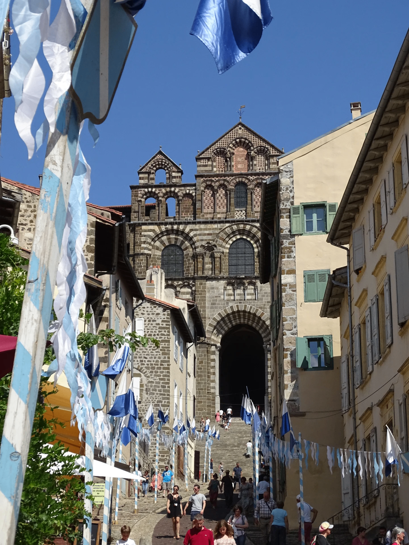 Rue animée décorée de drapeaux bleus et blancs menant à une cathédrale historique